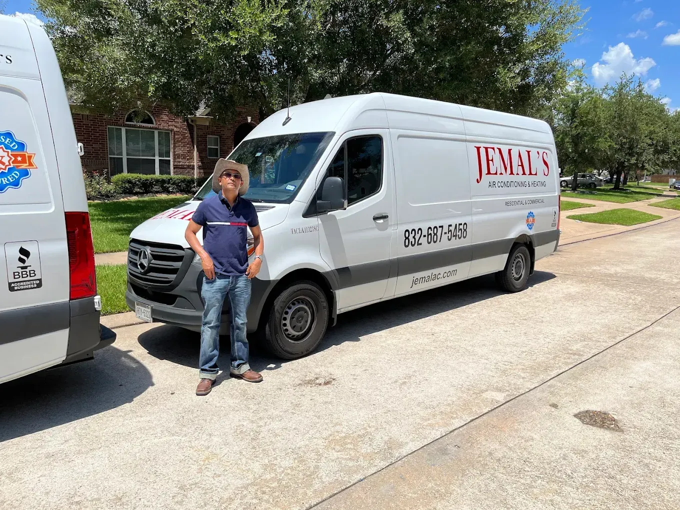 Person standing beside a white van on a sunny residential street