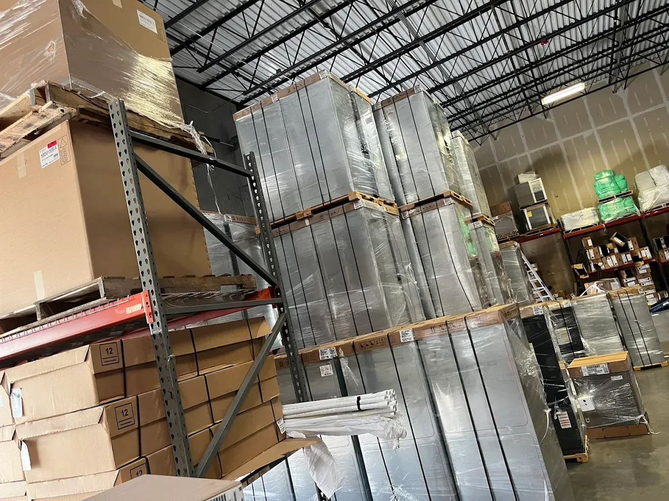 Warehouse aisle with stacked cardboard boxes and tall metal shelving under a high ceiling