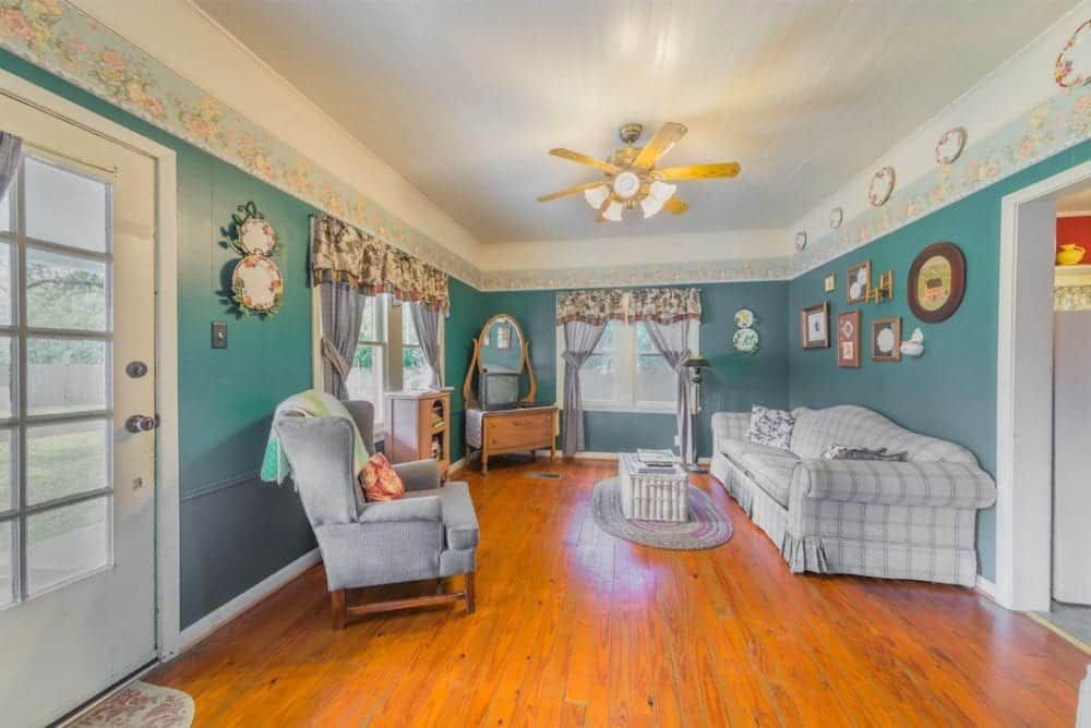 A living room with a couch , chair , table and ceiling fan.
