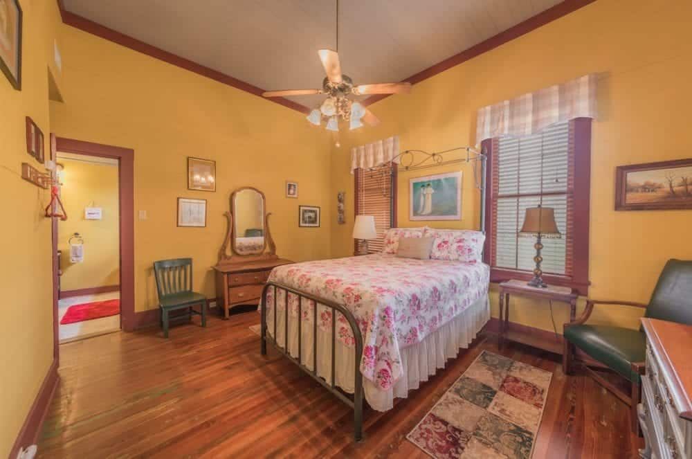 A bedroom with a bed , dresser , chair and ceiling fan.
