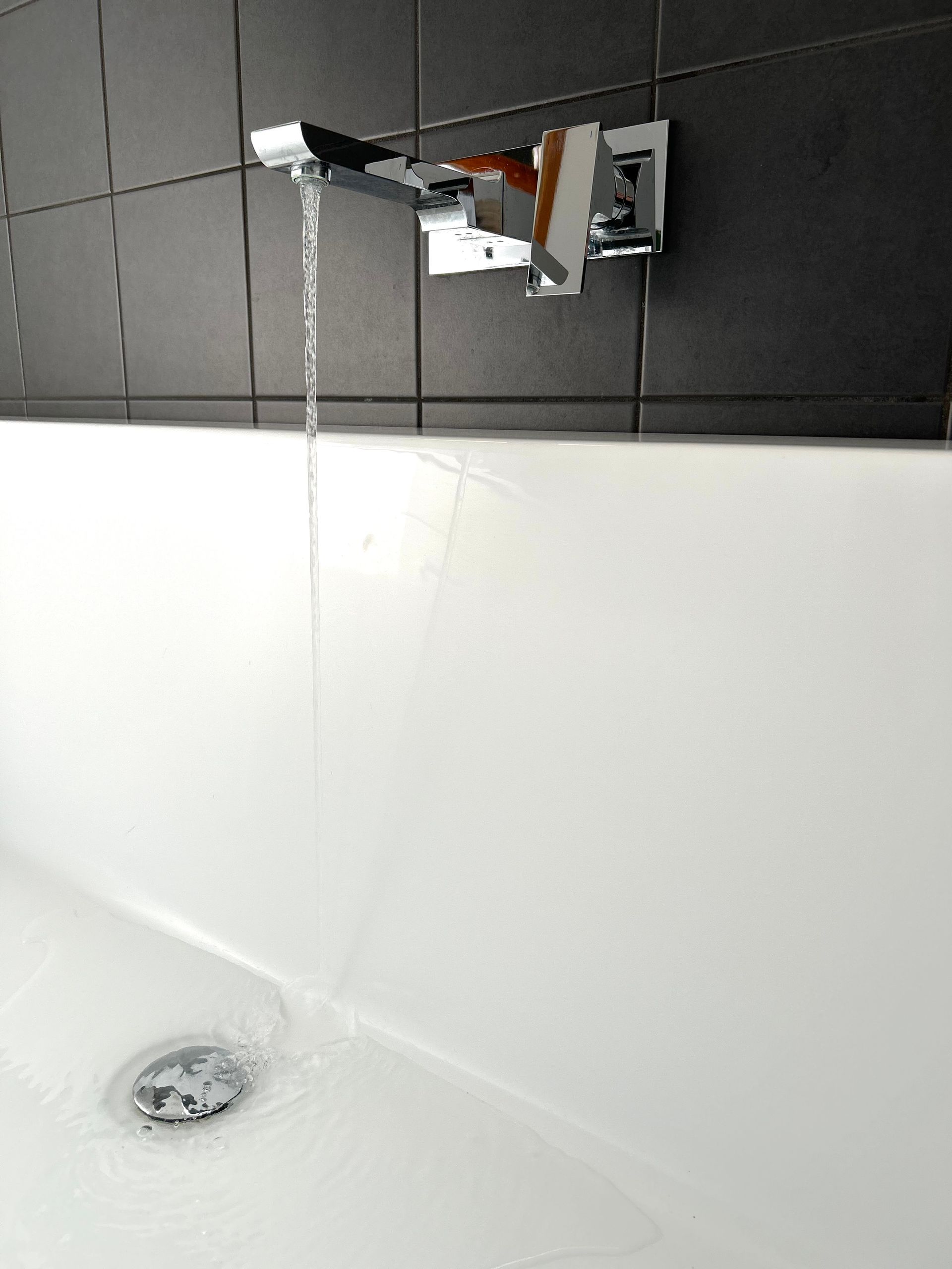 A Man Is Fixing A Sink In A Bathroom With A Wrench – Moore Creek, NSW - Thrift Plumbing Pty Ltd