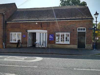 Brick building with white windows and a central entrance, beside a road on a sunny day