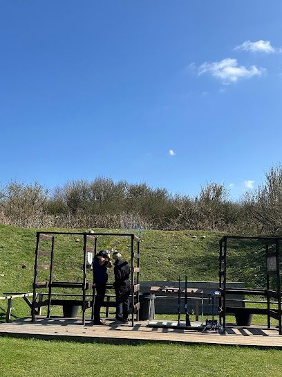 Two people by metal railings in a sunny outdoor park under a blue sky