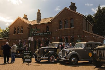 Vintage cars parked outside a brick church with people gathered in front.