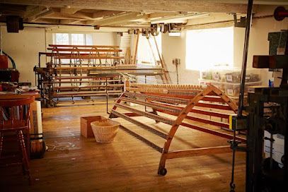 Sunlit workshop with wooden benches, shelves, and tools on a polished floor