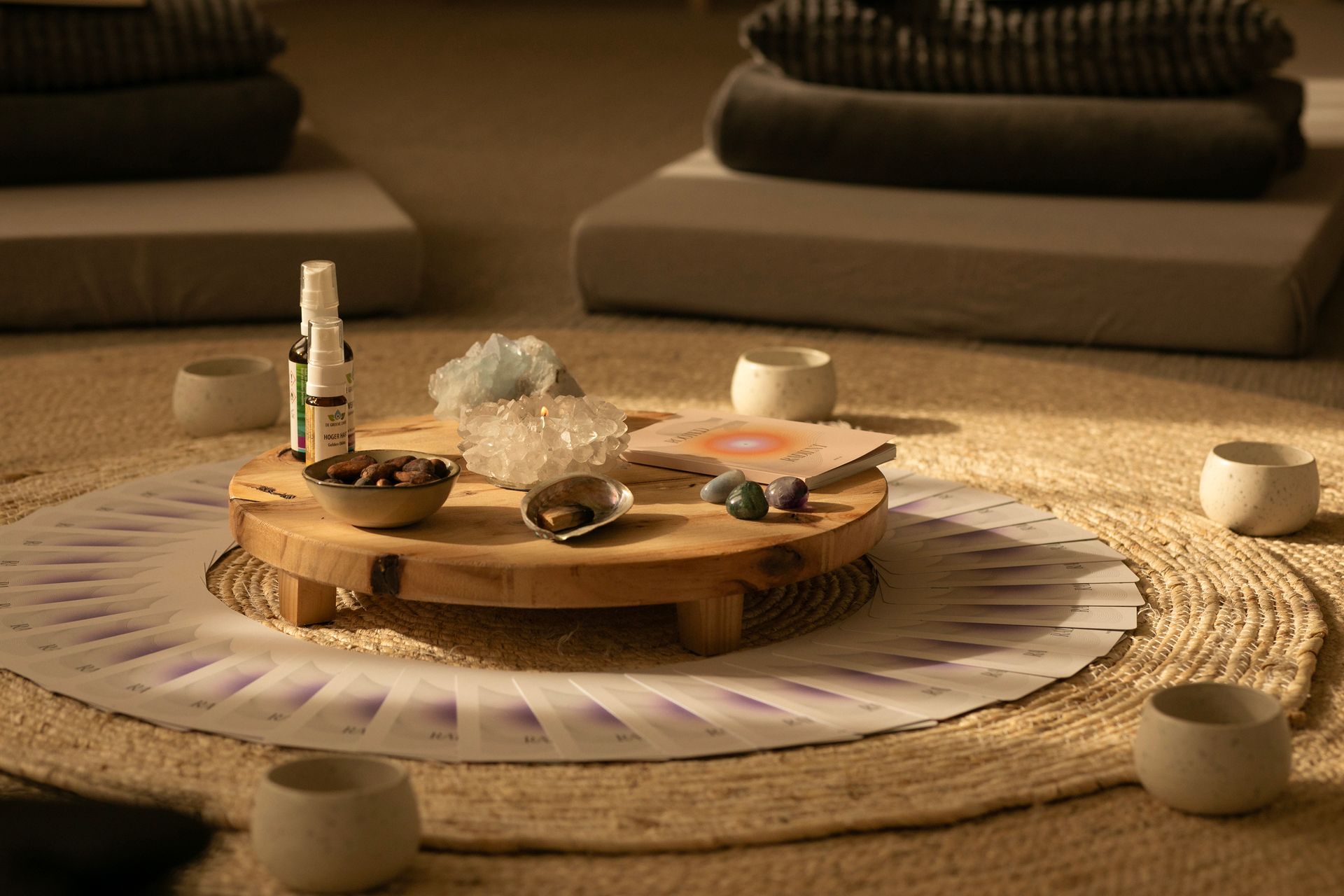 Een altaar met kaarsen, wierook en een kopje op een geweven mat in een serene kamer.