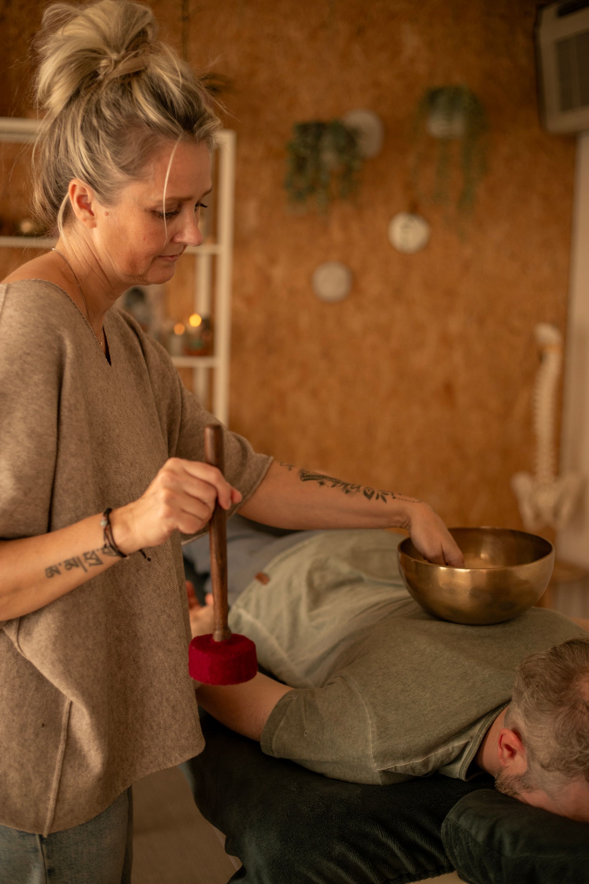 Persoon met een rode hamer naast een kom tijdens een geluidstherapiesessie.