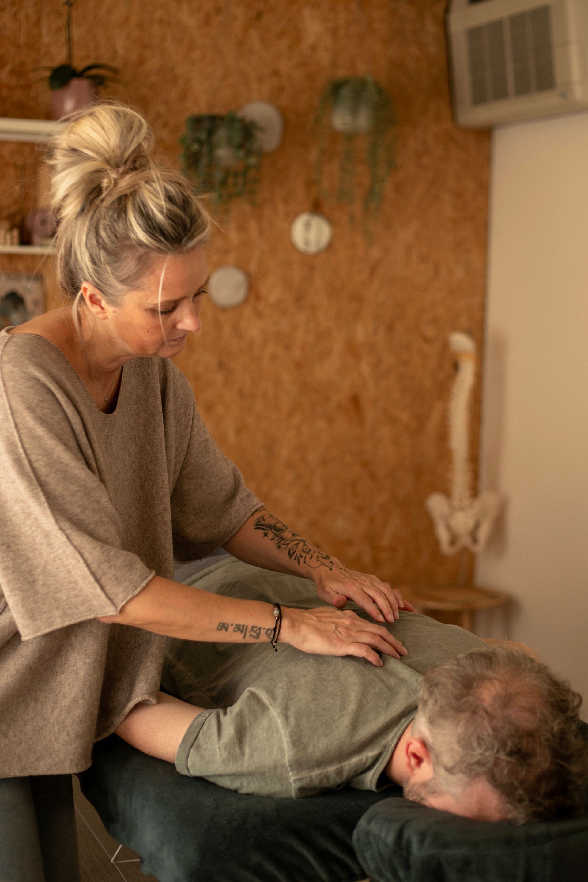Een holistische behandeling met een cliënt in een knusse ruimte met een warme, natuurlijke inrichting.