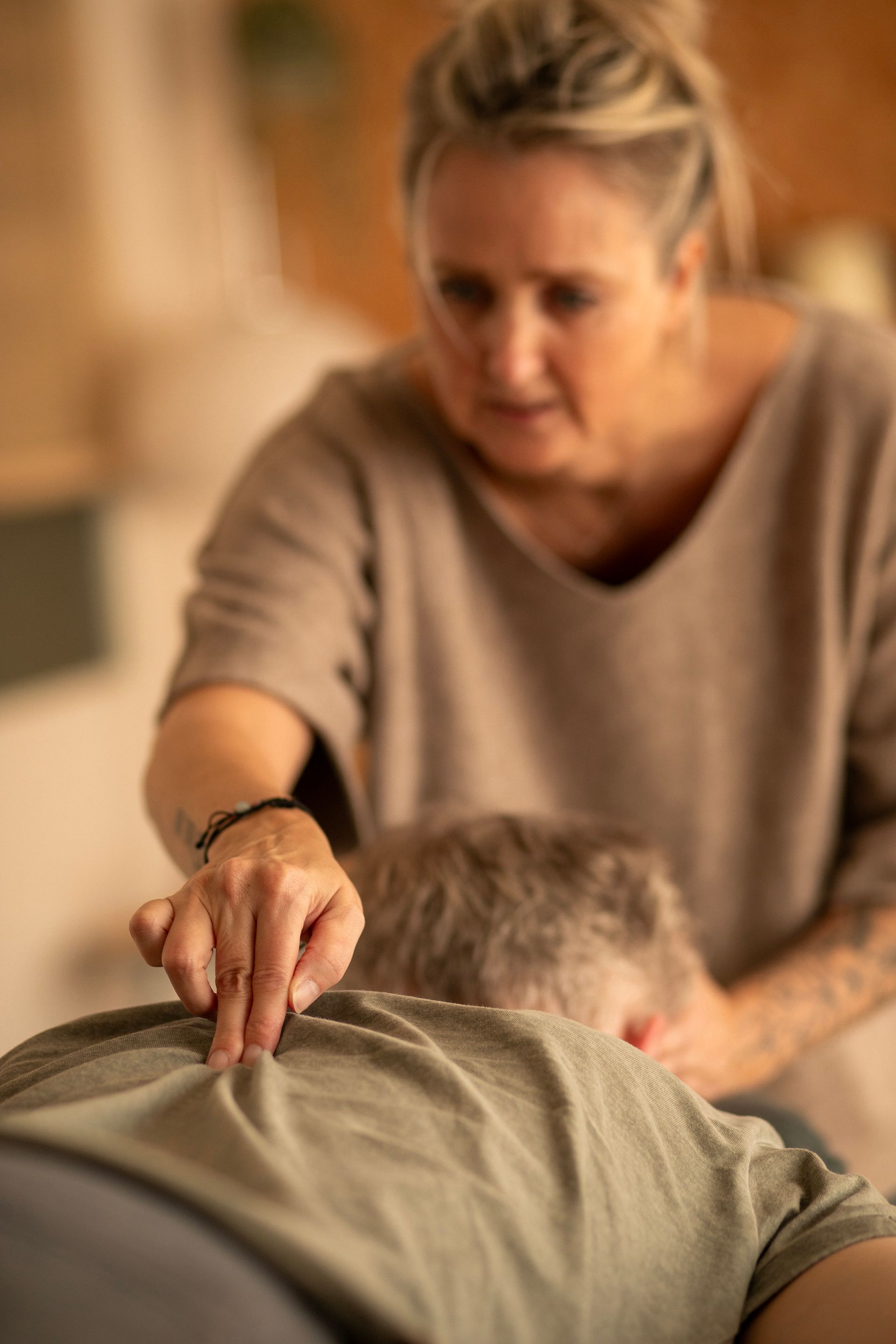 Een persoon ontvangt Spinal Flow van iemand anders in een warme, overdekte ruimte.