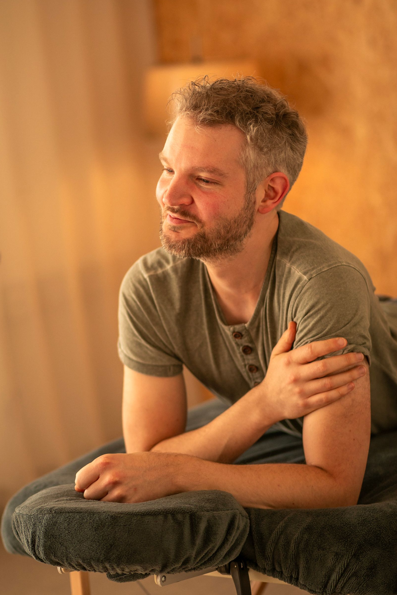 Een man ligt ontspannen op een massagetafel en houdt zijn arm vast in een sfeervol verlichte spa.