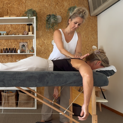 Een massagetherapeut behandelt een cliënt op een behandeltafel in een rustige spa-ruimte.