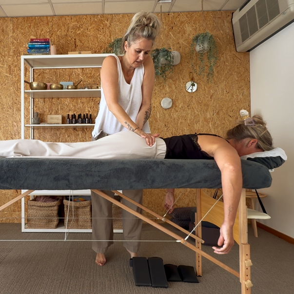 Een massagetherapeut behandelt een cliënt op een massagetafel in een gezellige spa-ruimte.