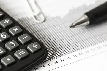 A pen is sitting on top of a calculator on a piece of paper.