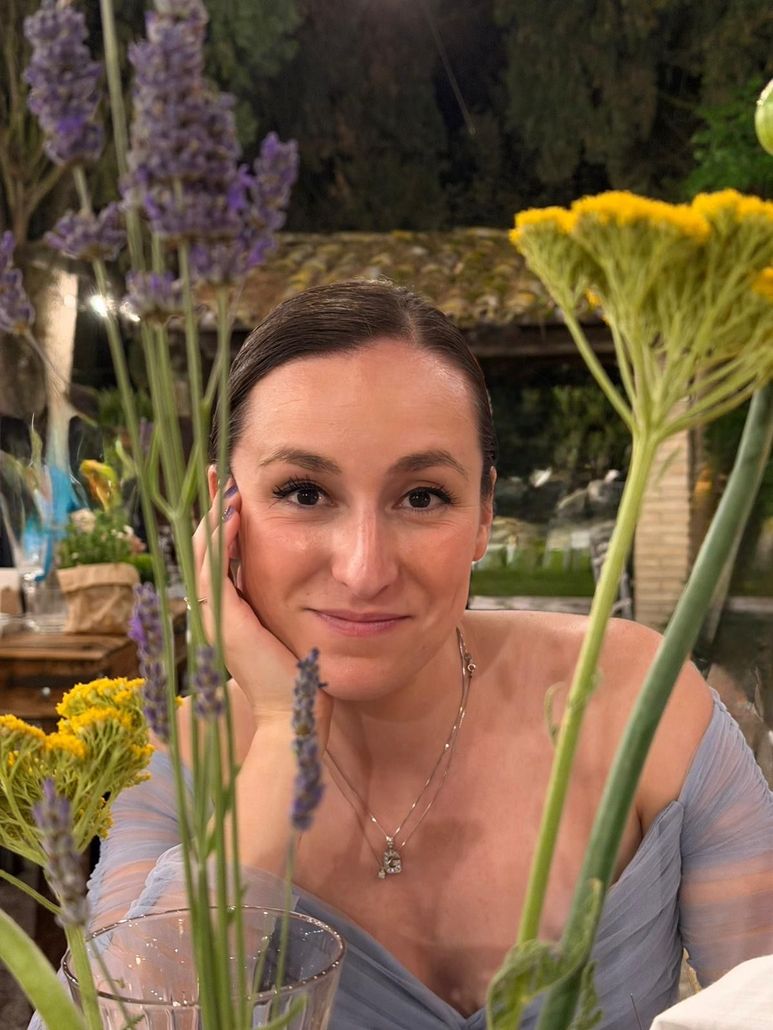 Woman smiling among tall wildflowers in a garden at dusk