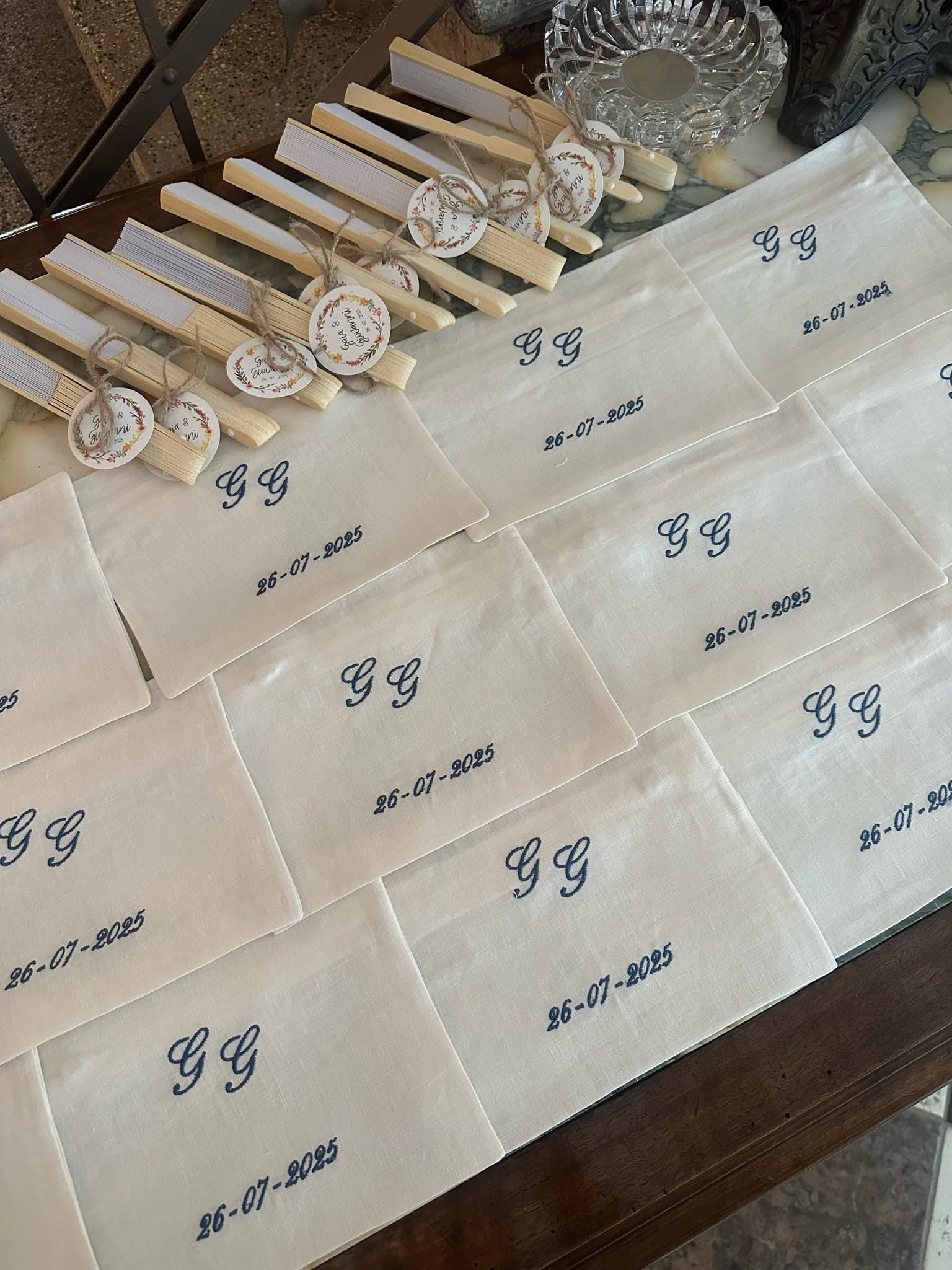 Assorted pastry-like items arranged in rows on beige cloth napkins with printed labels on a wooden surface.