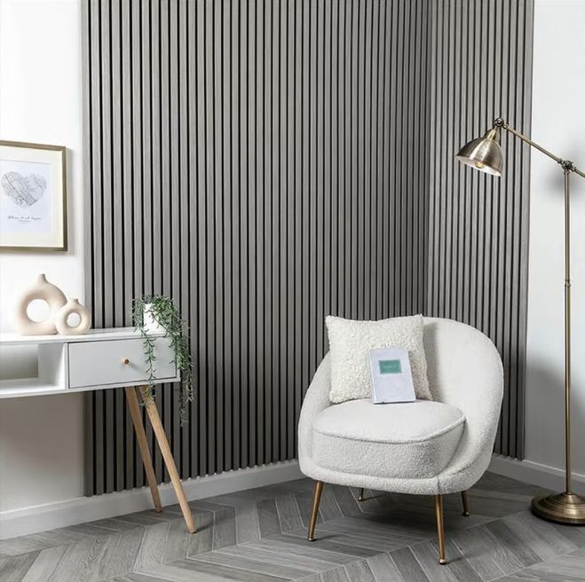 Sala de estar moderna en color gris con pared decorativa a rayas, silla blanca, lámpara de pie y escritorio pequeño.