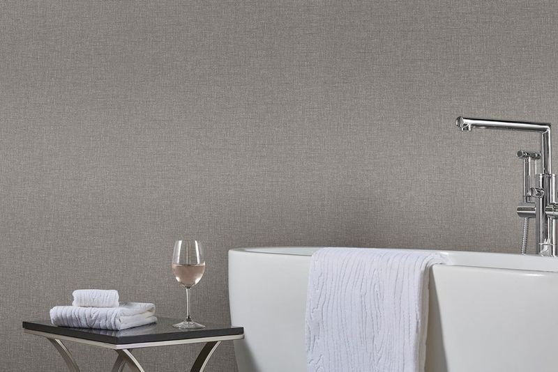 Baño minimalista con bañera independiente, toalla, mesita auxiliar y copa de vino.