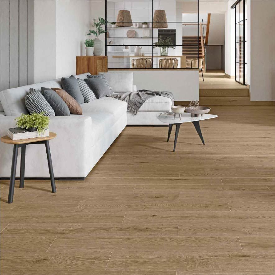 Sala de estar moderna con sofá blanco, cojines grises, suelo de madera y estanterías al fondo.