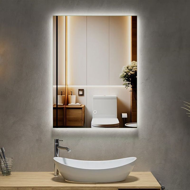 Baño moderno con tocador de madera, lavabo redondo sobre encimera y espejo grande iluminado.