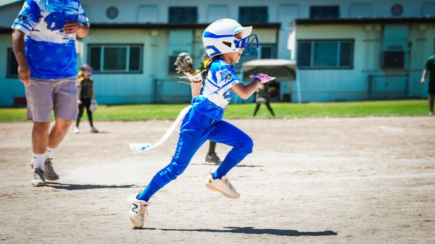 Baseball player sliding into home plate, catcher in front. Blue and gold uniforms, action shot.
