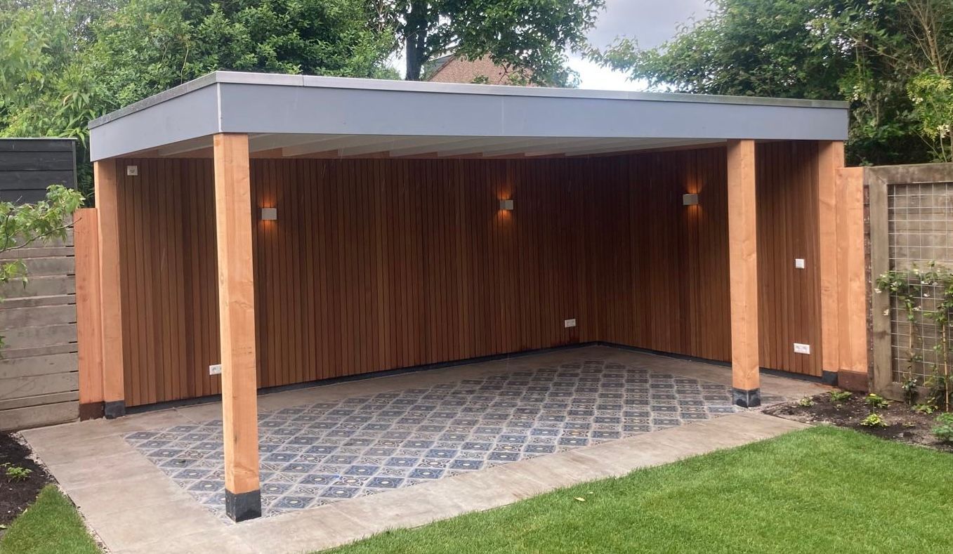 Een houten buitenlounge met een grijs plat dak, een vloer van natuursteen met een patroon, verticale houten lattenwanden en wandverlichting.