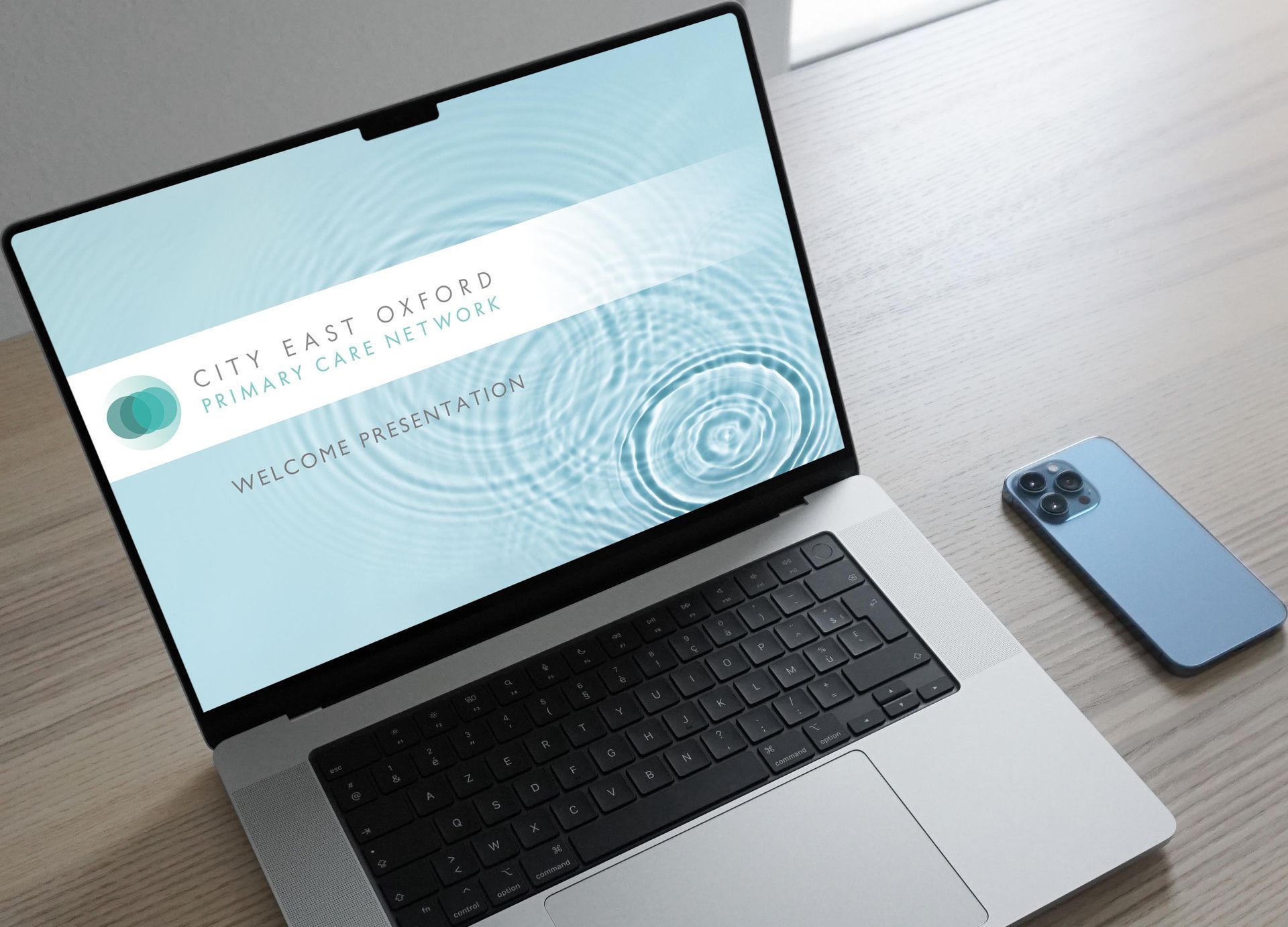 A laptop is open on a table next to a cell phone