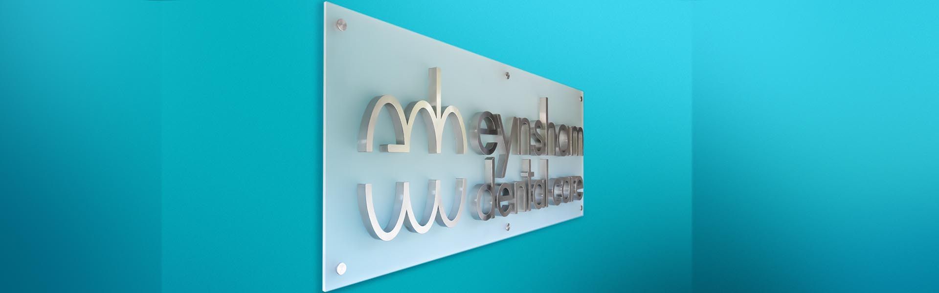 a sign on a blue wall that says 'eynsham dental care' on it