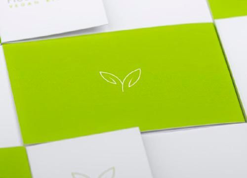 a close up of a green and white business card with a leaf on it .