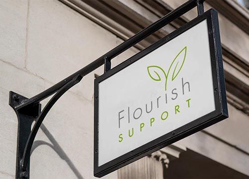 a sign for flourish support is hanging from the side of a building .