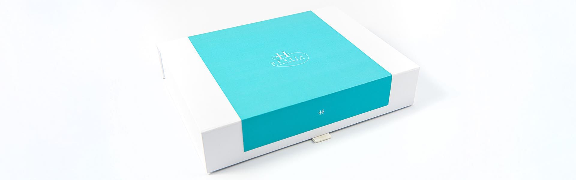 a white needlework  box with a blue stripe for hestia needlework