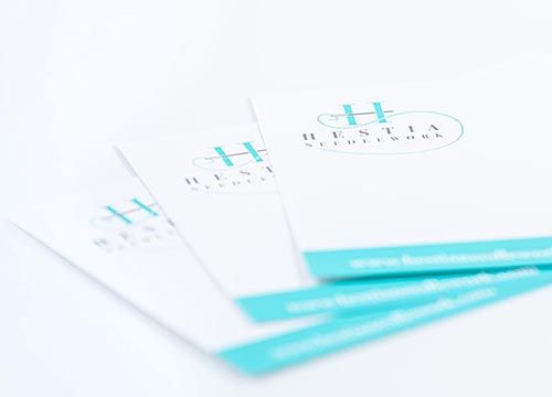 Three business cards are stacked on top of each other on a white surface.