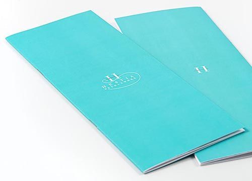 Two blue brochures are stacked on top of each other on a white surface.