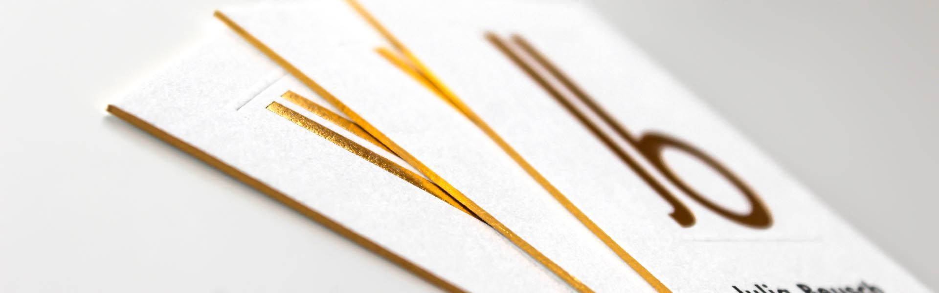 a close up of a gold foil edged business card with the letters jb on it
