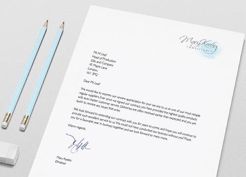 a letter is sitting on a table next to two pencils .