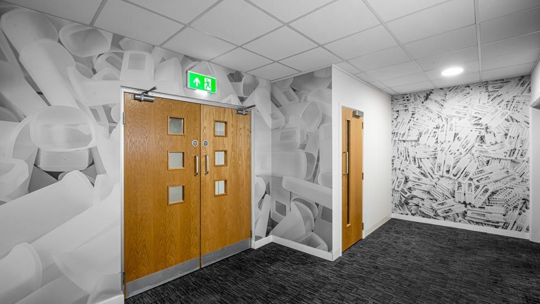 a hallway with a large format photographic wallpaper with a green exit sign on the wall