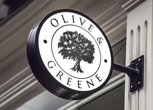 a black and white sign with an olive tree on it is hanging on a building .