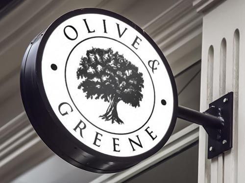a round sign with a tree logo for olive and greene on it is hanging on a wall.