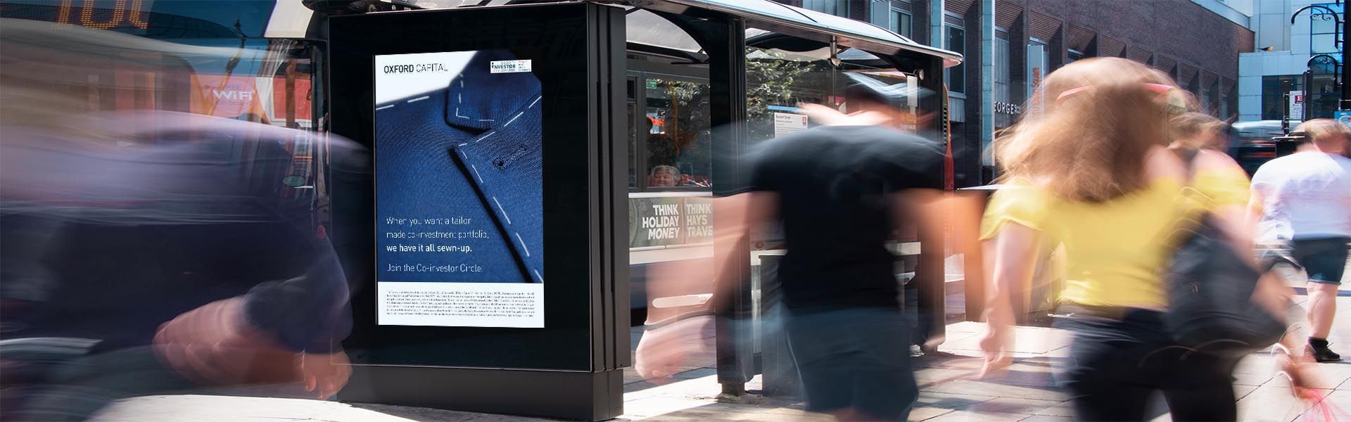 a blurry picture of people walking in front of a an advertisement for oxford capital