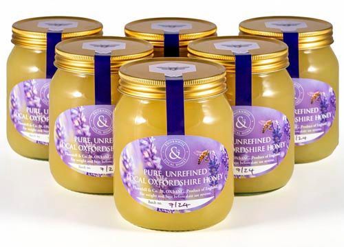 a group of jars of honey with purple labels are sitting on top of each other on a table.