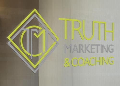 the logo for truth marketing and coaching is on a glass wall .