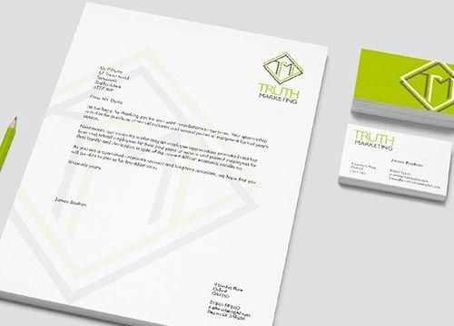 a letterhead , business cards , and a pencil are on a table .