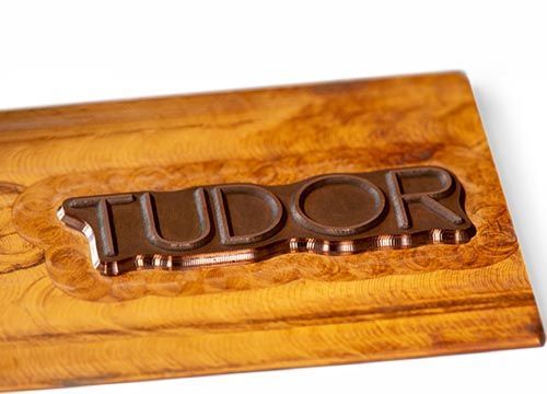 a copper embossing die with the word tudor milled out of it .