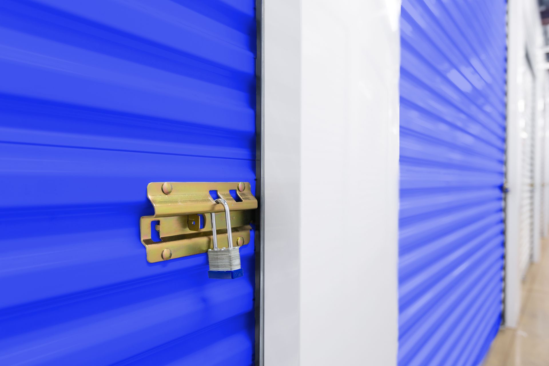 Blue storage unit door secured with a brass padlock and latch