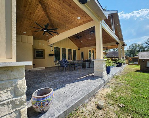 A large covered patio with a ceiling fan and a potted plant.