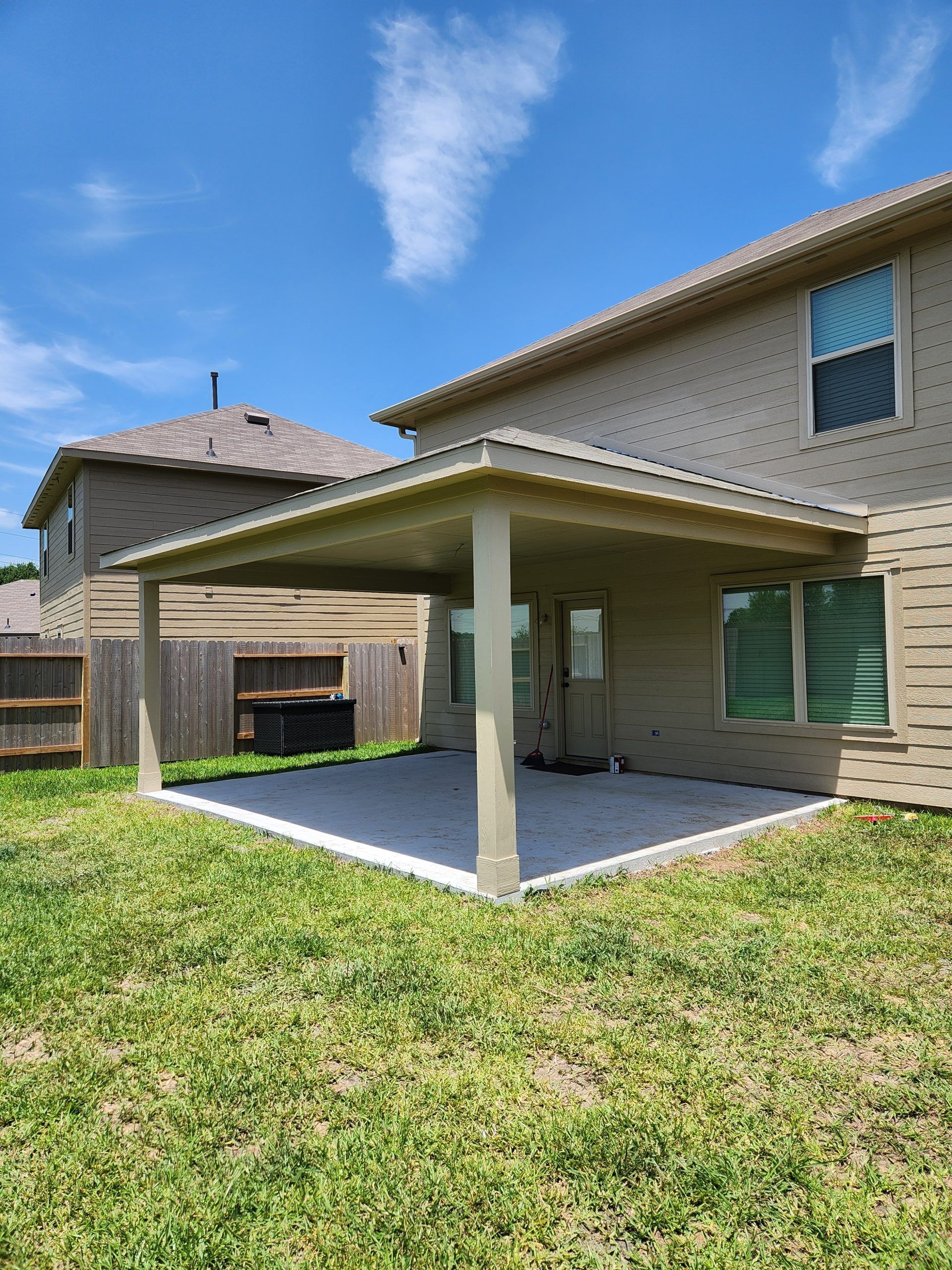 There is a covered patio in the backyard of a house.
