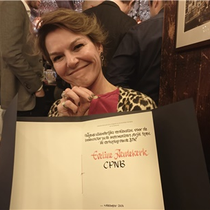 Lachende vrouw met een bord met handgeschreven tekst op een evenement binnenshuis.