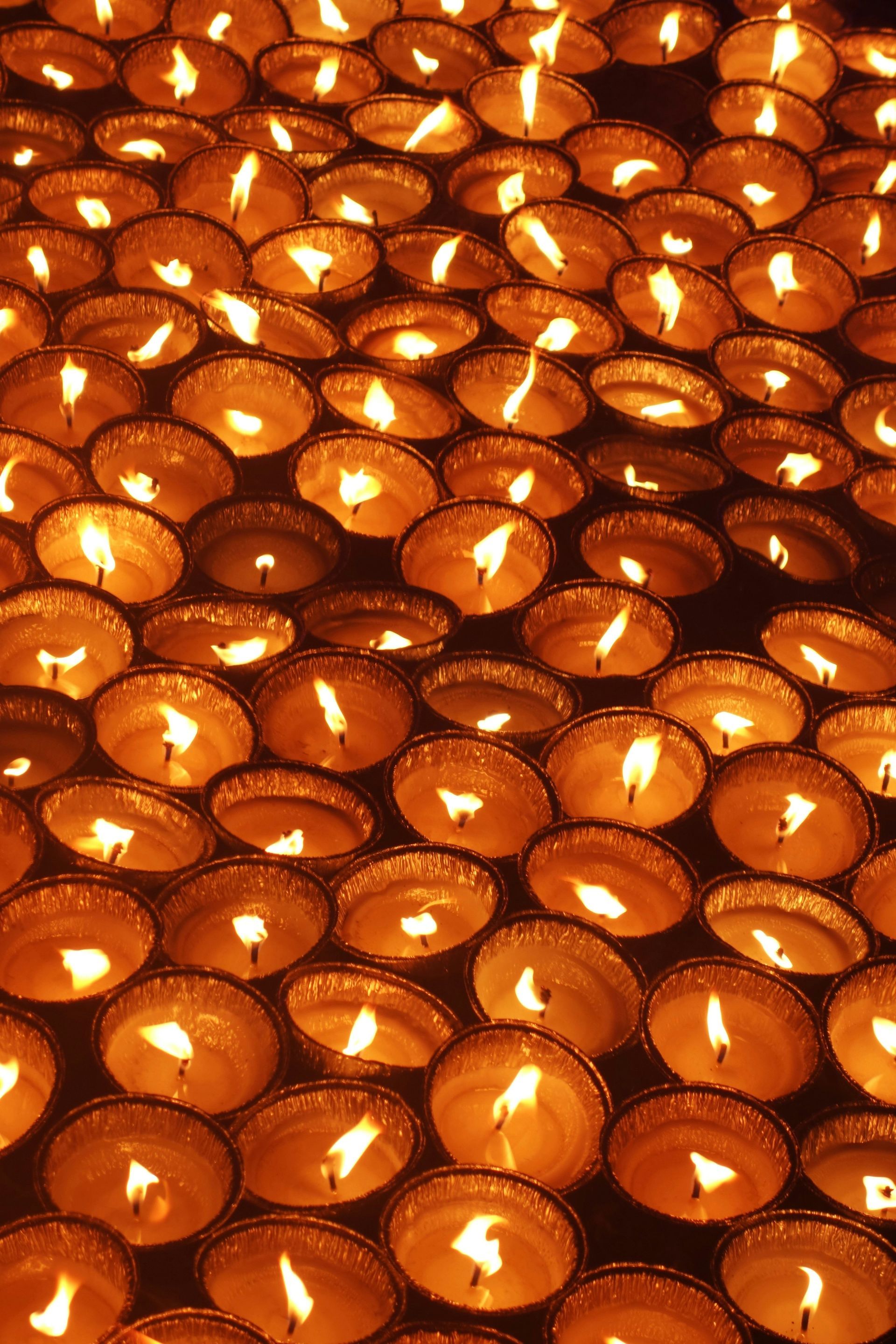 Lit candle with blurred lights in the background. Warm glow in dim setting.