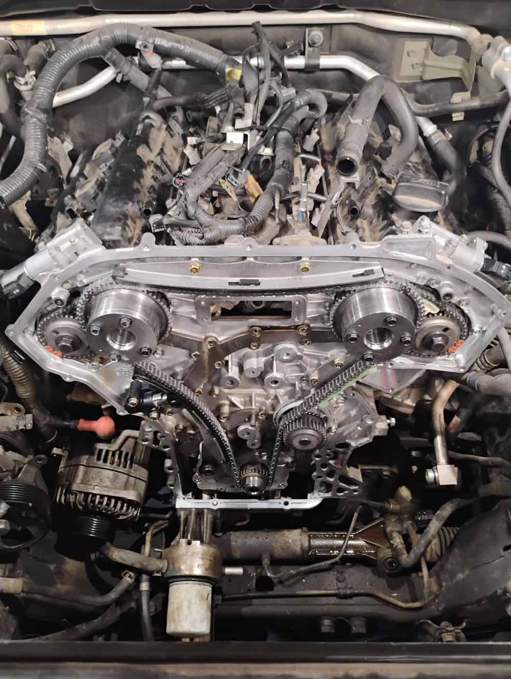 Car engine with timing components exposed. Black engine block, silver components. Open setting.