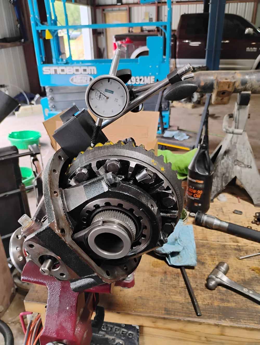 Differential assembly with a dial indicator for measuring gear backlash in a repair shop.