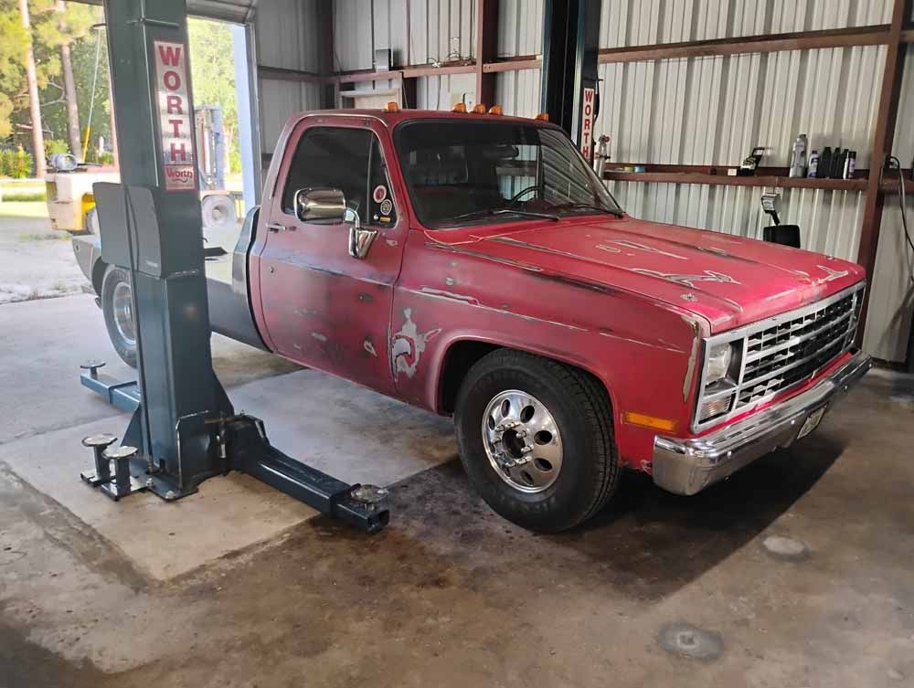 Red Chevrolet truck on a lift in a garage.